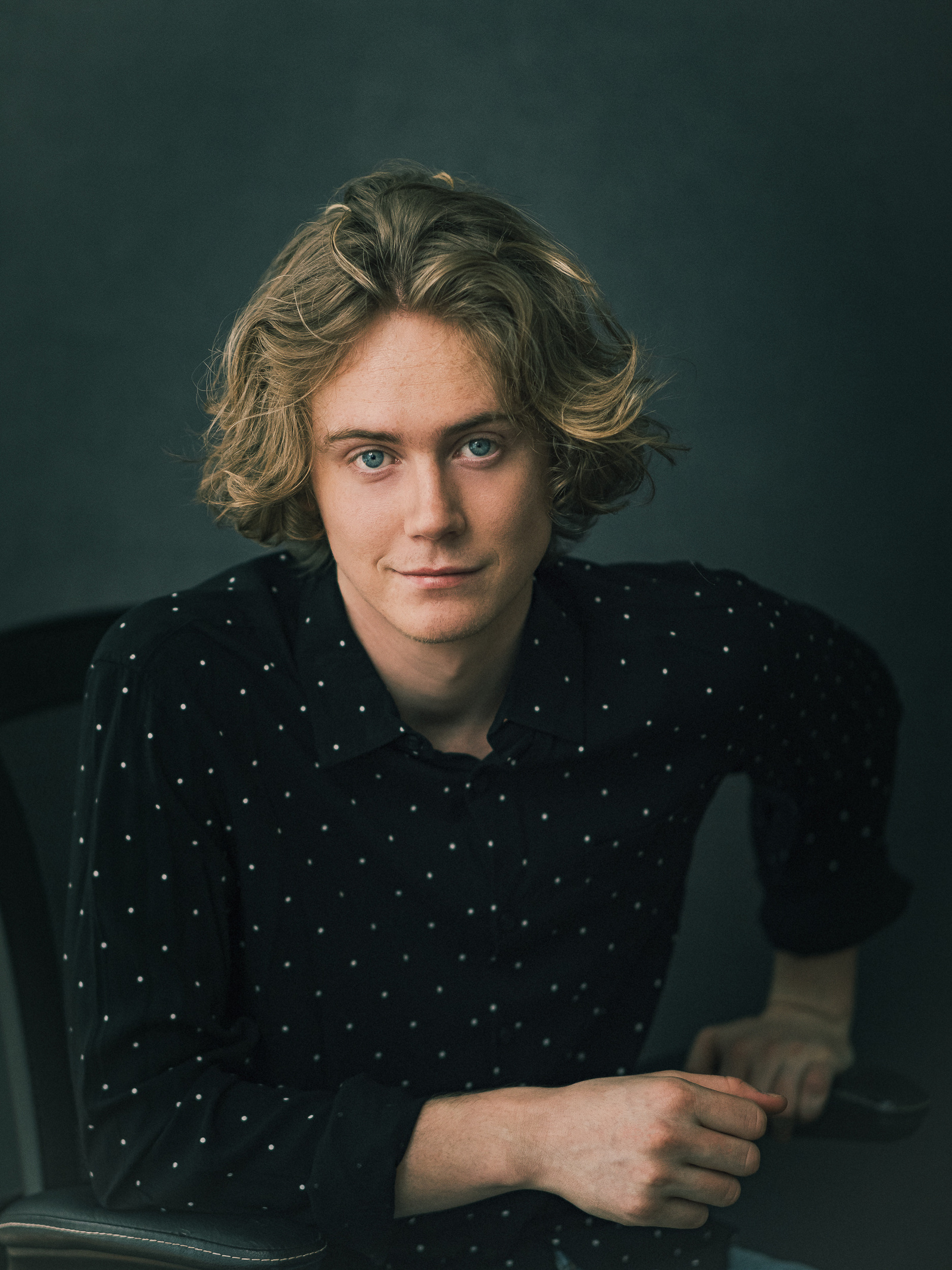 Headshot of a male actor wearing a black shirt against a dark background