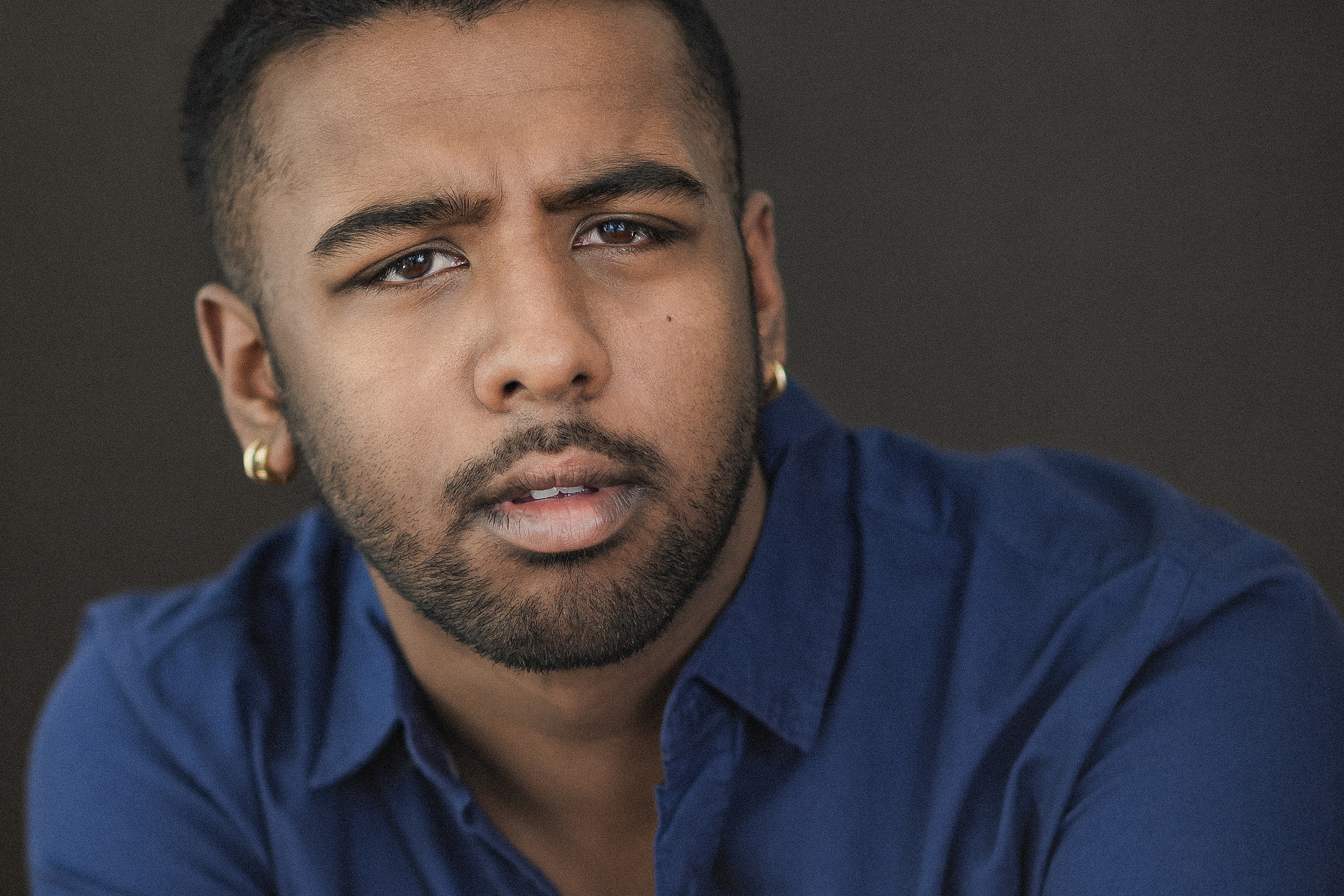 Headshots of a male actor wearing a blue shirt against a dark background