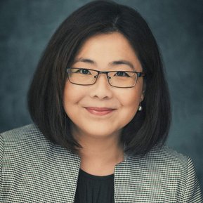 Headshot of a female Brisbane actor wearing glasses on a grey/blue background