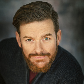 Headshot of a male Brisbane actor with a beard on a grey background