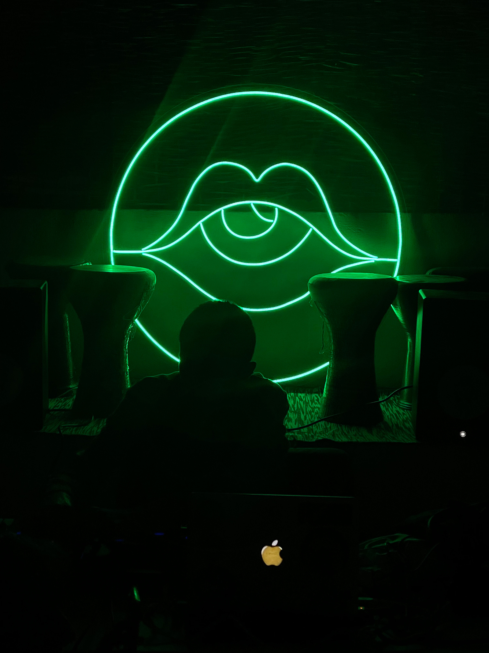 Dark image with the Underground Social icon in neon green, behind the silhouettes of four goblet drums and a deejay, in front of a controller and laptop.