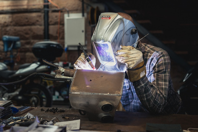 Motorcycle tank welder wearing a mask