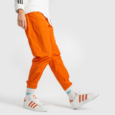 Adidas trainers on a female model wearing baggy orange cargo pants in a studio