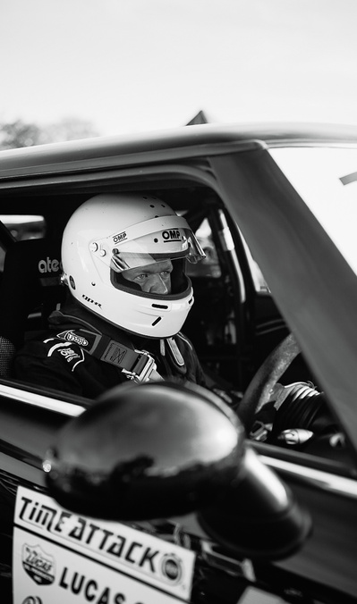 Time Attack UK car racer with a white helmet on wearing race overalls ready to race sitting in his Mini R56 Cooper John Cooper Works race car.