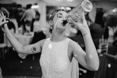 Bride, on the dancefloor at the blazing donkey, drinking a bottle of wine