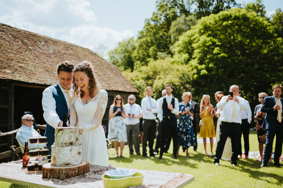 amazing cutting of the cake at the papermill in kent. The newley married couple are having laughing with the cake with all their wedding guests watching in enjoyment