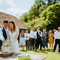 amazing cutting of the cake at the papermill in kent. The newley married couple are having laughing with the cake with all their wedding guests watching in enjoyment