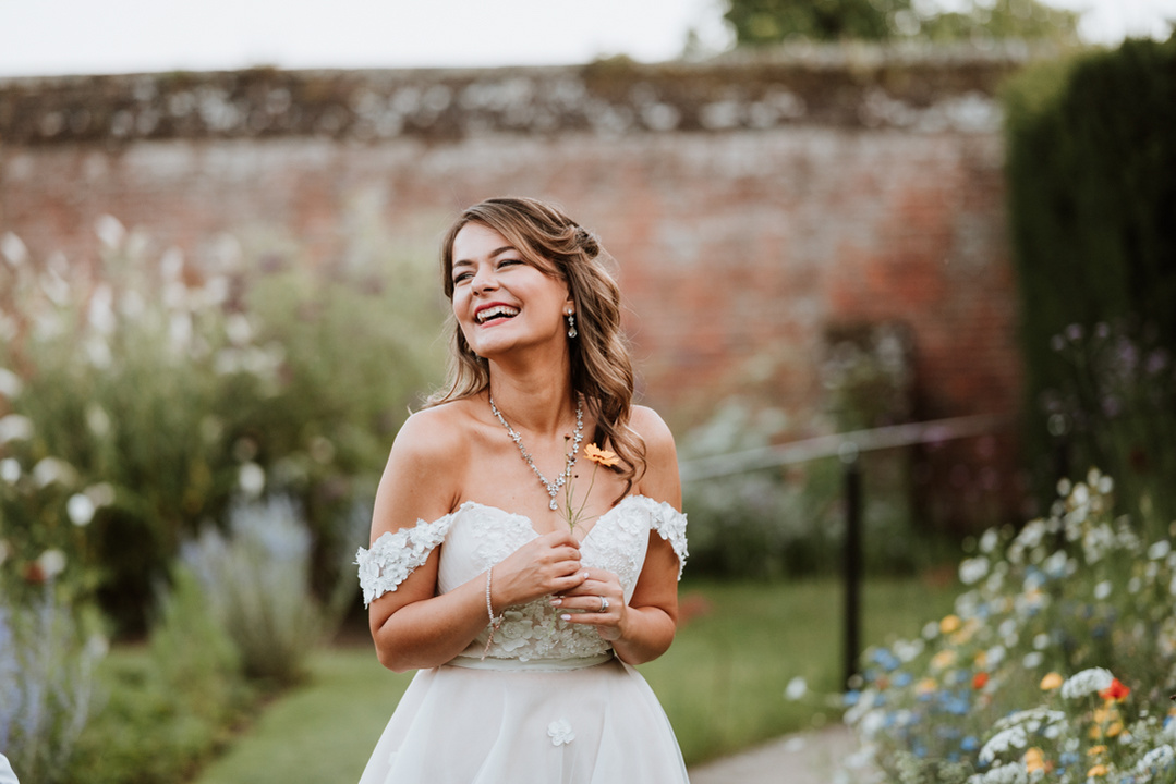 bride laughing in a beautiful garden outside a kent castle on her wedding day