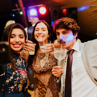a candid photo of wedding guests on the dance floor taking a selfie together whilst drinking gin on the dance floor in kent