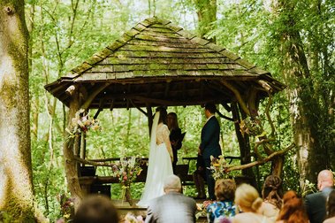 groom and bride under the wooden ceremony area at the paper mill kent