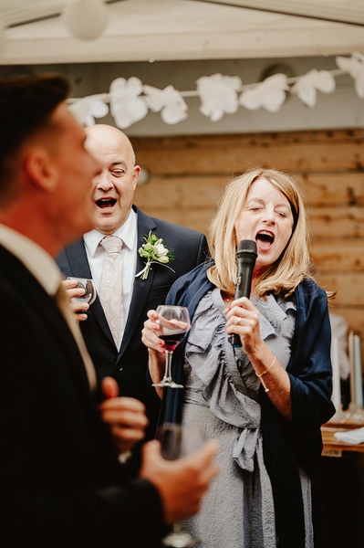 Father and mother of the bride at wedding singing karaoke outdoors