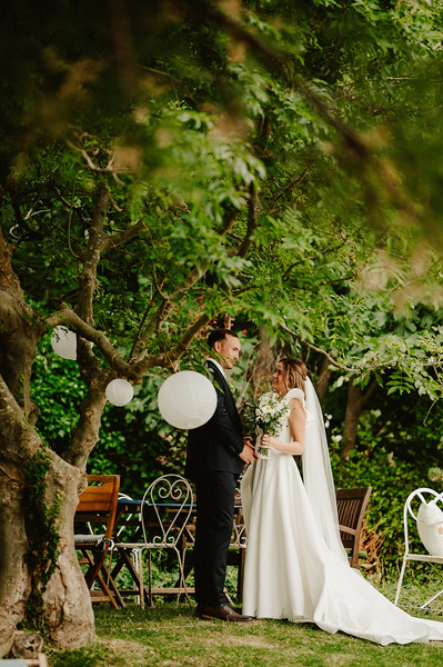 Candid unplanned photograph of bride and groom standing under a tree at Beacon house