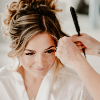 a soft focus wedding photograph of a bride having her hair styled on her kent wedding day whilst wearing white night wear