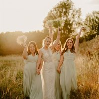 relaxed bridesmaids during golden hour holding their flowers up above their heads whilst walking towards kent wedding photographer and laughing trying not to fall over