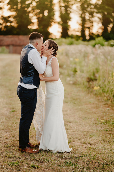 Outdoors during sunset at the night yard the bride and groom share a emotional kiss