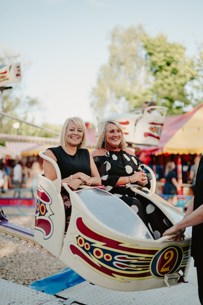 Wedding guests are smiling on a ride at the funfair at Marleybrook House