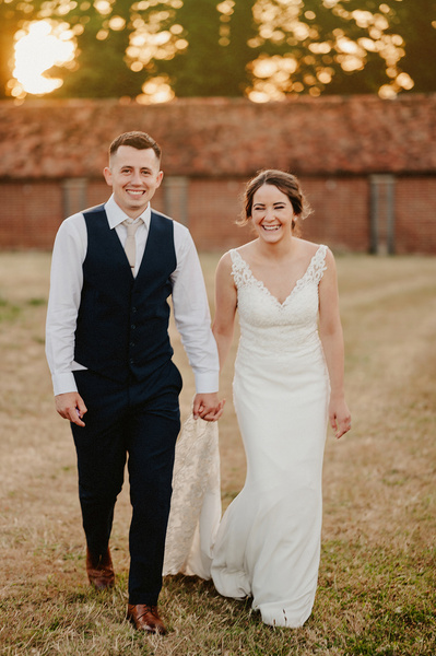 Bride and groom during sunset smiling at the camera whilst walking the night yard