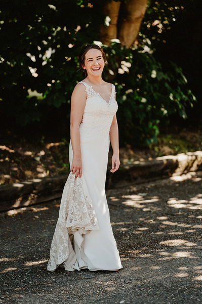 Gorgeous bride in white dress laughing for unposed photograph in open shade at the night yard