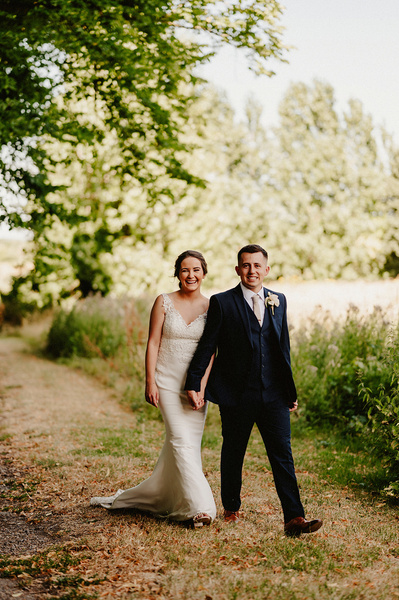 Bride and groom holding hands walking outside at the night yard