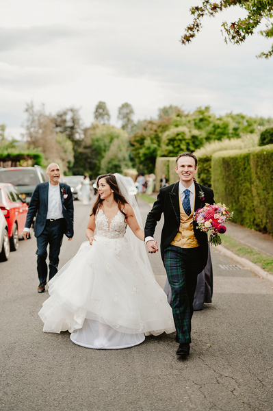 bride and groom holding hands walking up a street in Kent to their Indian wedding reception
