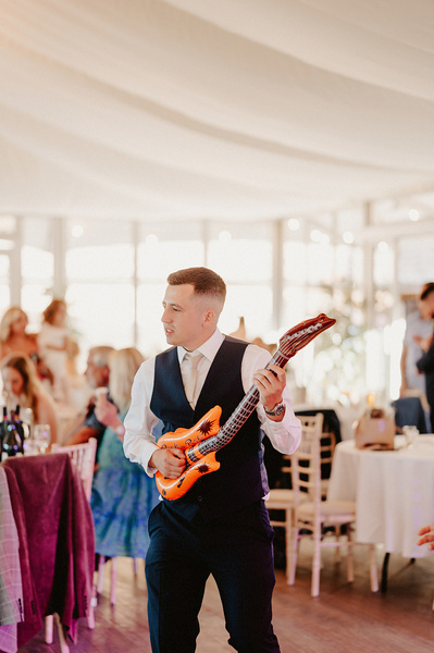 groom dancing at the night yard with an inflatable guitar on the dance floor