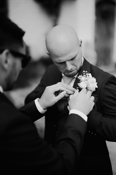 gRoom on his Kent wedding day at Marleybrook House black-and-white photo of him having his flowers put on his jacket
