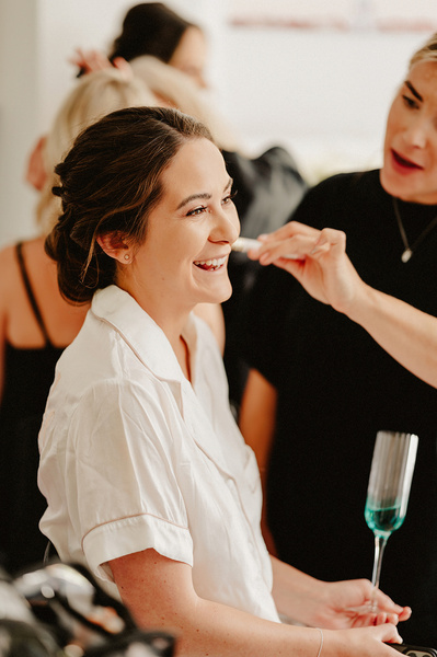 A bride laughing and joking while having her make up done