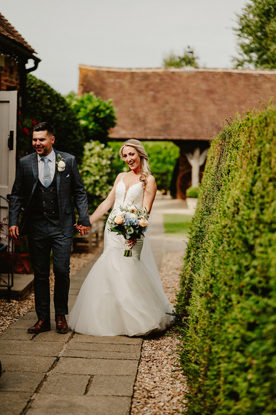 bride and groom walking along a hedge row outdoors at winters barns