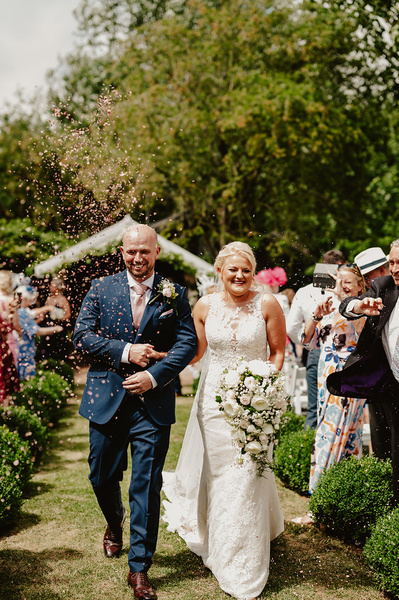 Bride and groom and walk down the aisle whilst being showered with confetti at Marleybrook House