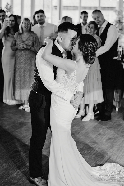 bride and groom share a kiss in a black and white photo at the night yard