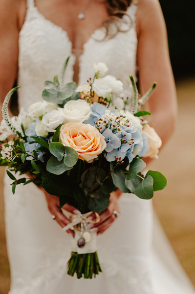bridal flowers held out in front of the brides white dress at winters barns