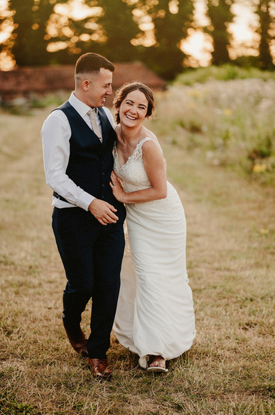At the night yard bride and groom are walking towards the camera laughing and joking falling onto each othe
