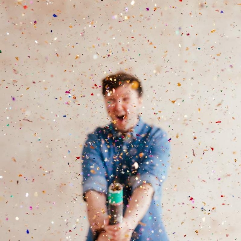 Confetti Canon explodes leaving man blurry smiling in the background