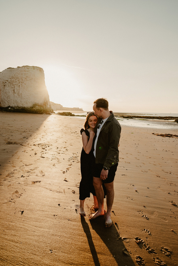 Man and woman embrace on botany Bay with a sunset in the background