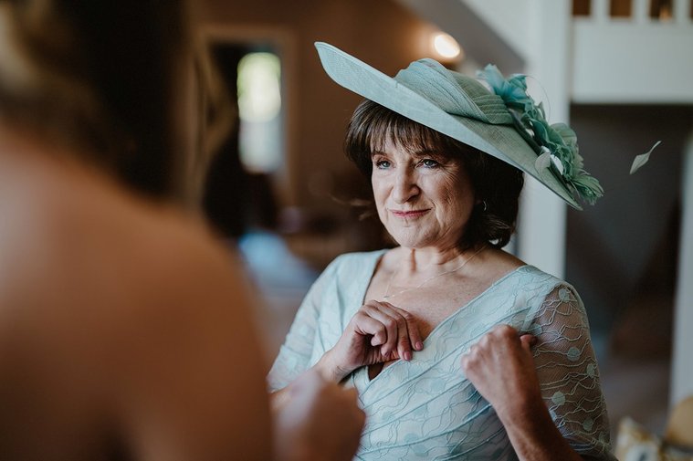 mother of the bride in natural window light smiling at her daughter the bride