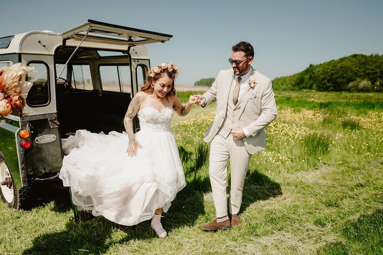 Bride in gorgeous dress being helped out of wedding car at the wilderness kent