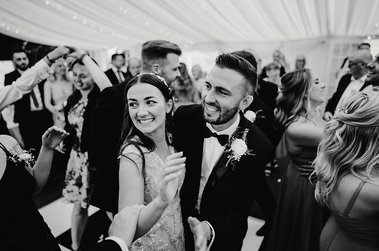 Black and white documentary wedding photo of a bride and groom dancing on a busy dance floor at the cave hotel wedding venue in kent