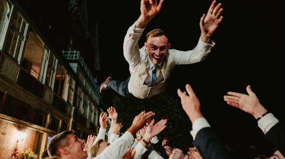 groom being thrown into the air by groomsmen on his wedding day