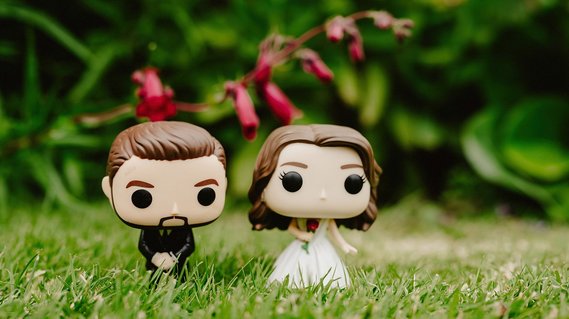 funko pop! figures of the bride and groom outside on grass at broome park in kent with shallow depth of field