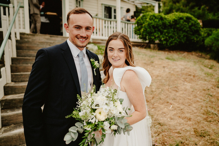bride and groom smile outside a rustic wedding venue in kent