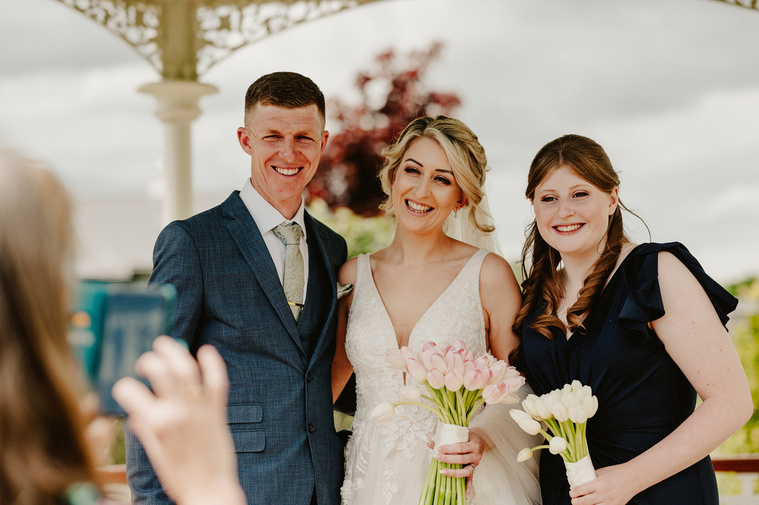 A spontaneous snapshot of the bride posing with wedding guests, blissfully unaware that the wedding photographer is also capturing the genuine, candid moment