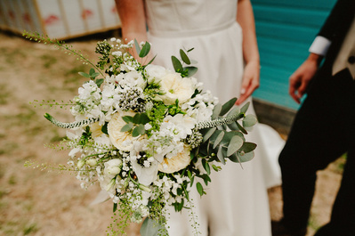 Bride holds her bouquet down the side of her dress