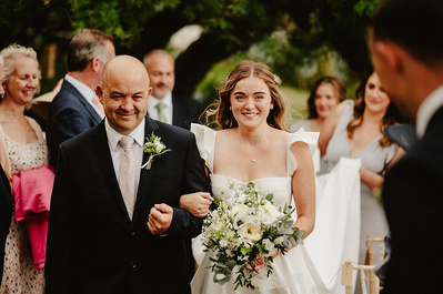 Bride and her father walking down the aisle during wedding outdoors