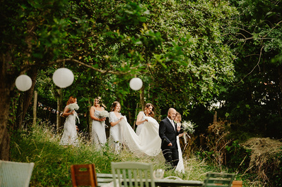 Bride walks through the gardens with her bridal party at Beacon house