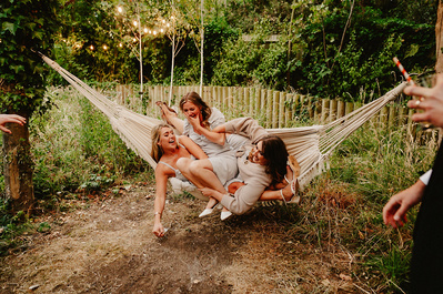 Bridesmaids fall out of hammock outside in the gardens of the Kent wedding venue Beacon house