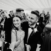 black and white photo of smiling bride and groom enjoying the chaos of the dance floor at the cave hotel during kent wedding reception