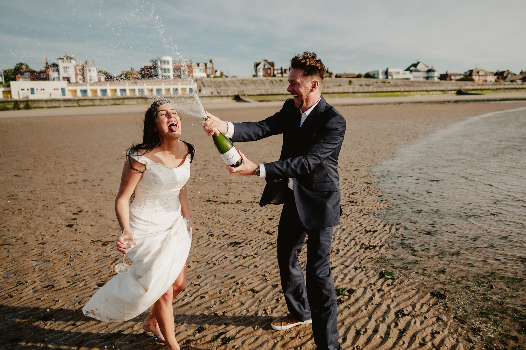groom on west bay kent sprays champagne into brides mouth during fun wedding photography portraits