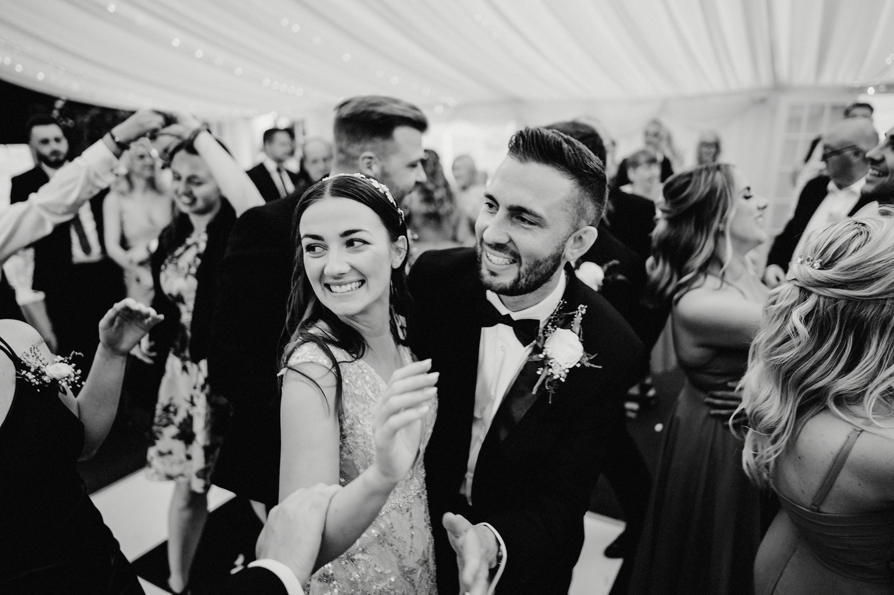 black and white photo of smiling bride and groom enjoying the chaos of the dance floor at the cave hotel during kent wedding reception