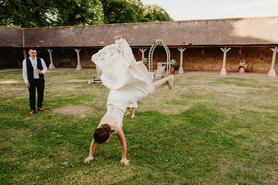 at the night yard a bride in her wedding dress tries out a cartwheel with groom laughing at the challenge