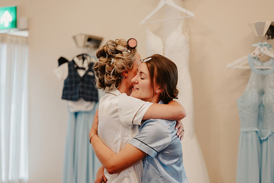 Bride and bridesmaid hugging emotionally